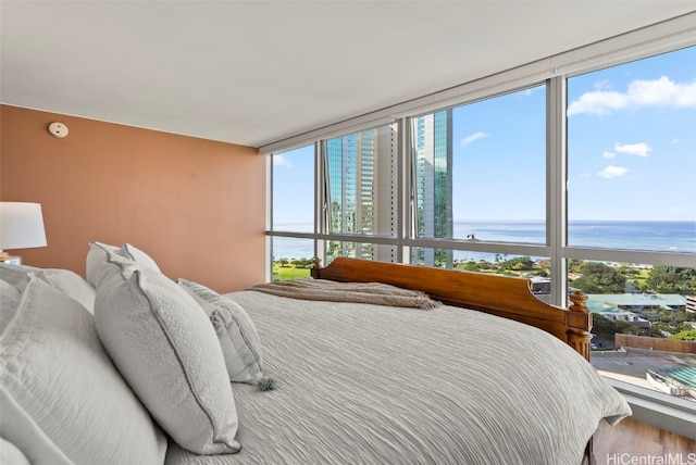 bedroom featuring a water view, wood-type flooring, expansive windows, and multiple windows