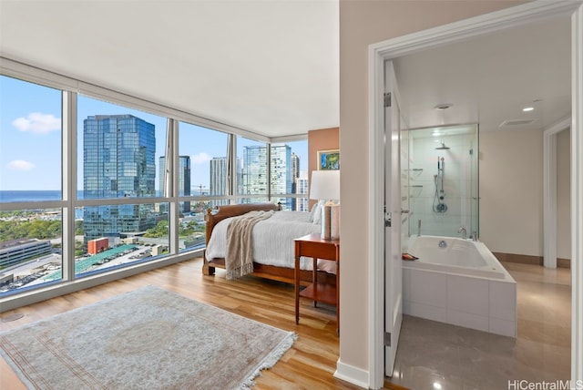 bedroom featuring expansive windows, ensuite bathroom, and light hardwood / wood-style floors