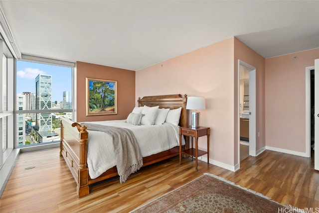 bedroom featuring expansive windows and hardwood / wood-style floors