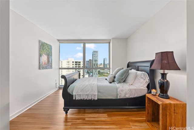 bedroom with hardwood / wood-style floors and expansive windows