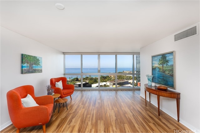 sitting room with a wall of windows, wood-type flooring, and a water view