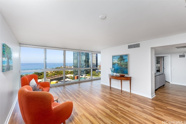 living room featuring expansive windows, a water view, and hardwood / wood-style floors