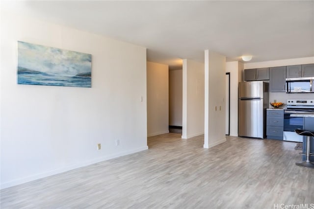 kitchen with stainless steel appliances, light hardwood / wood-style floors, and gray cabinetry