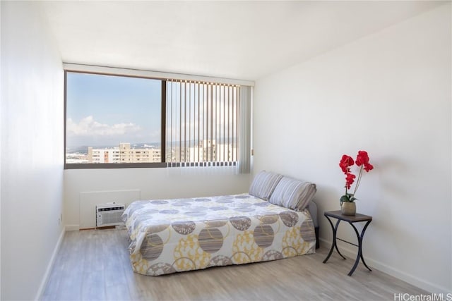 bedroom featuring a wall unit AC and light wood-type flooring