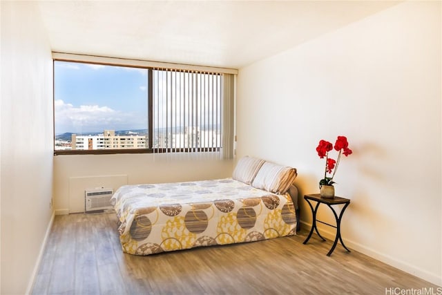 bedroom featuring a wall mounted AC and hardwood / wood-style floors