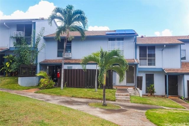 view of front of home with a front yard and solar panels