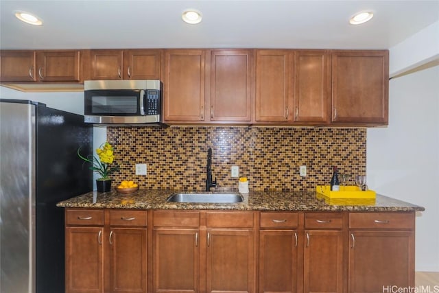 kitchen featuring appliances with stainless steel finishes, sink, dark stone countertops, and decorative backsplash