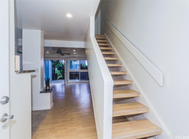 stairs featuring hardwood / wood-style flooring and ceiling fan