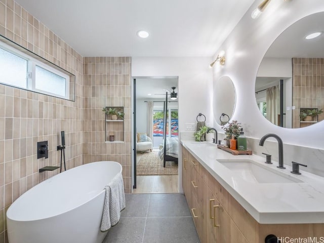 bathroom with tile walls, a healthy amount of sunlight, tile patterned flooring, and a bathing tub