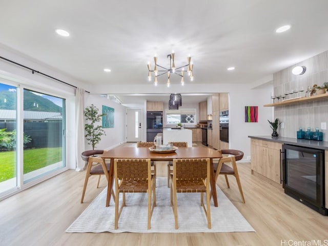 dining space featuring an inviting chandelier, light hardwood / wood-style flooring, beverage cooler, and indoor bar