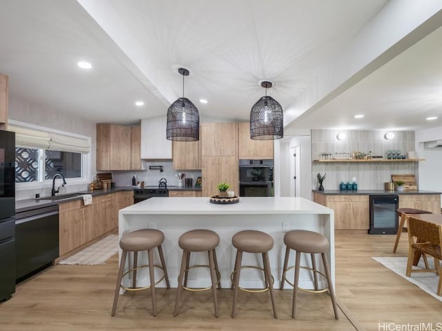 kitchen featuring beverage cooler, hanging light fixtures, a kitchen island, and black appliances