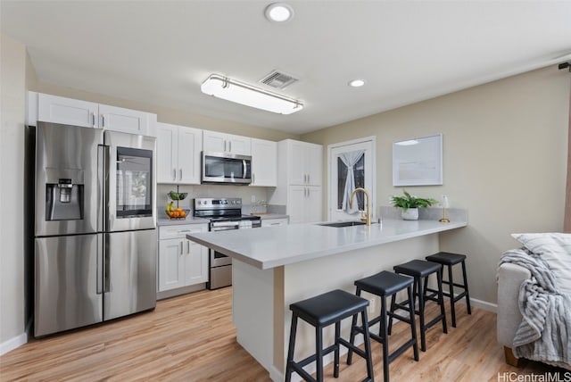 kitchen with a sink, visible vents, white cabinetry, appliances with stainless steel finishes, and a kitchen bar