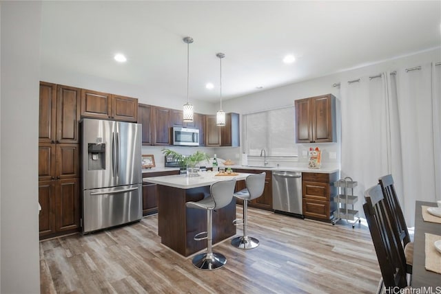 kitchen with sink, a breakfast bar area, a center island, appliances with stainless steel finishes, and pendant lighting