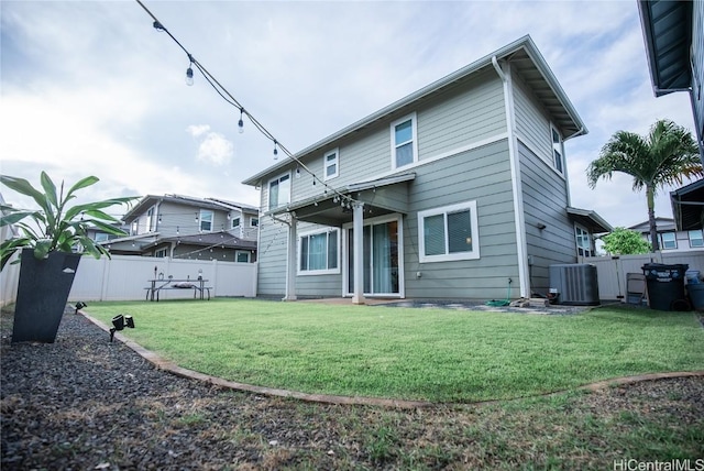 rear view of property featuring a lawn and central air condition unit