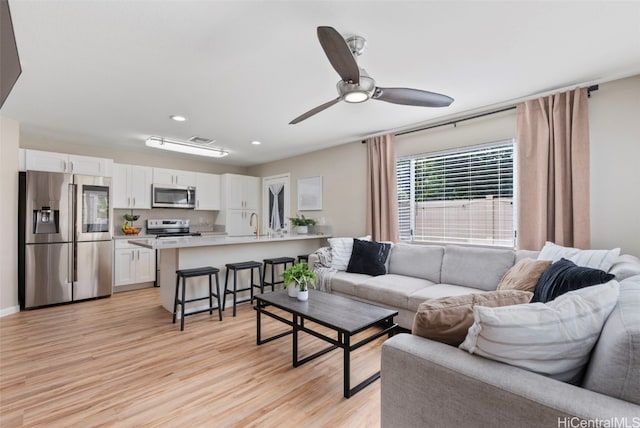 living room with ceiling fan, light wood-style flooring, and recessed lighting