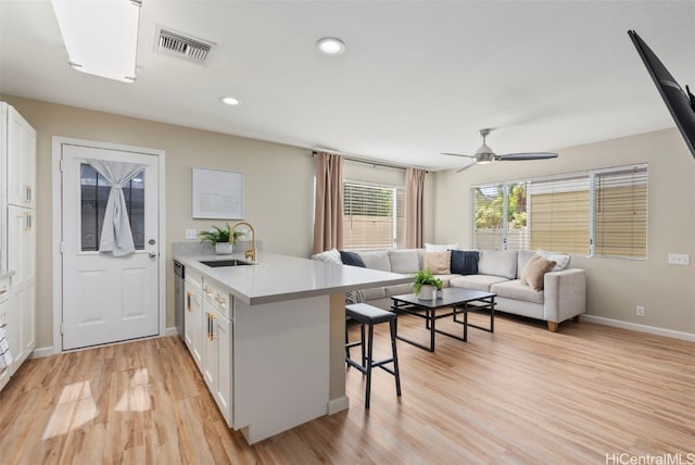 kitchen with a peninsula, a sink, visible vents, open floor plan, and a kitchen bar