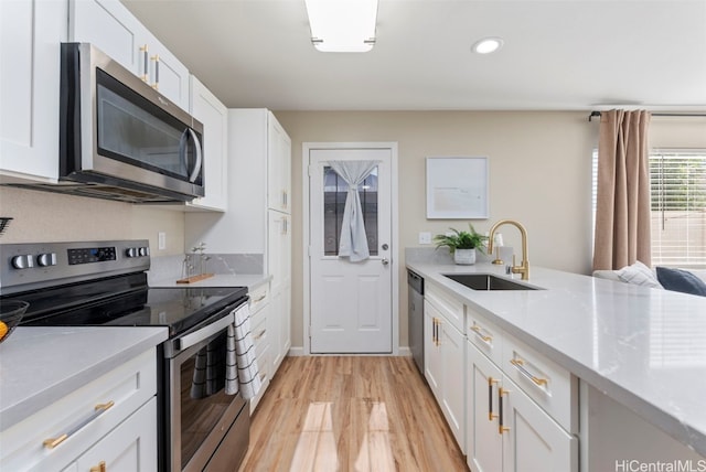 kitchen with stainless steel appliances, a sink, light countertops, and white cabinetry