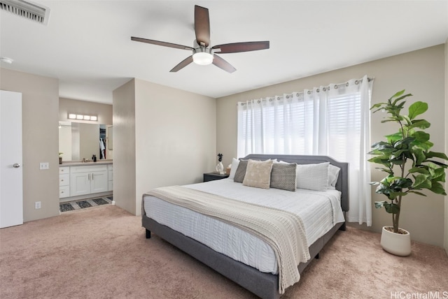 bedroom with ceiling fan, visible vents, ensuite bathroom, and light colored carpet