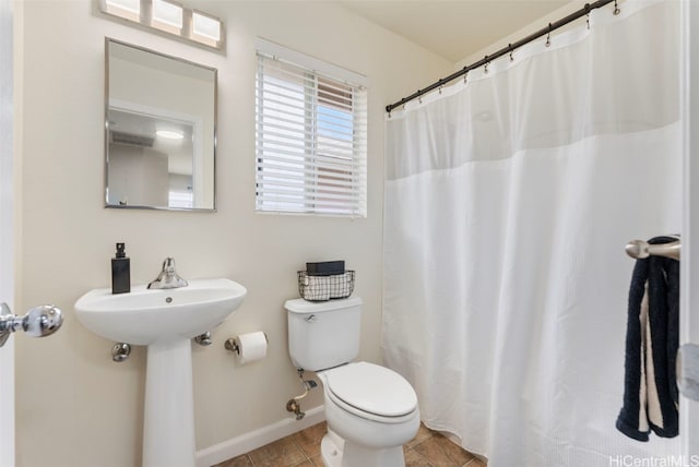 full bathroom with curtained shower, toilet, a sink, tile patterned flooring, and baseboards