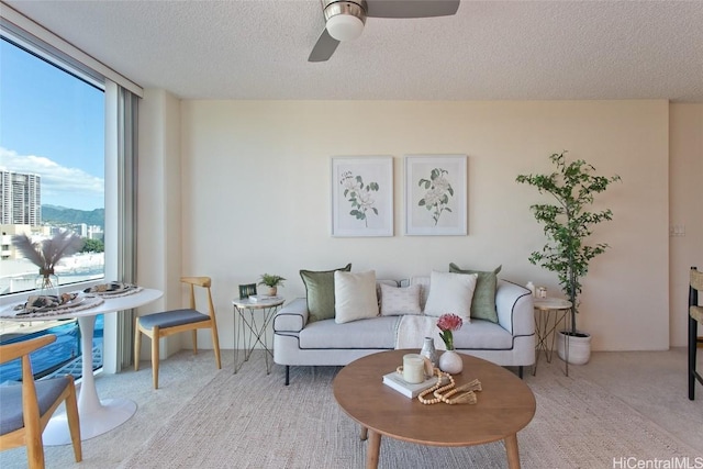 carpeted living room with ceiling fan and a textured ceiling