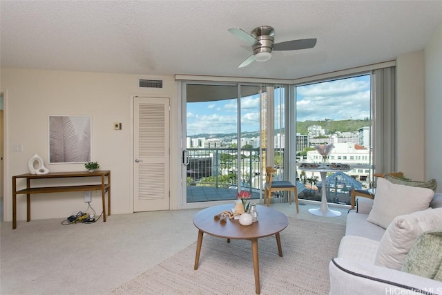 carpeted living room featuring ceiling fan, expansive windows, and a textured ceiling