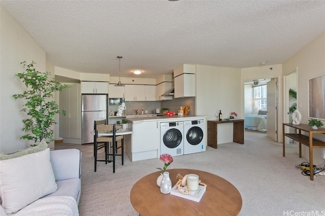 interior space with light colored carpet, washer and clothes dryer, and a textured ceiling