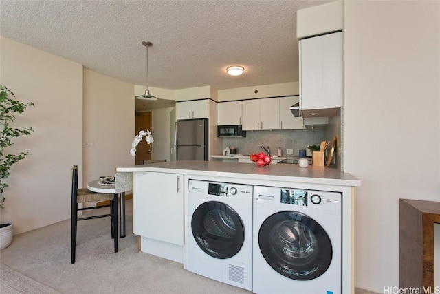 laundry room with separate washer and dryer, light carpet, and a textured ceiling