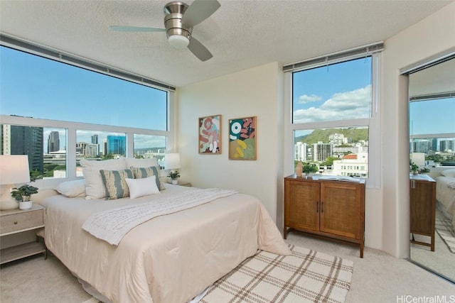 carpeted bedroom featuring a textured ceiling, expansive windows, and ceiling fan