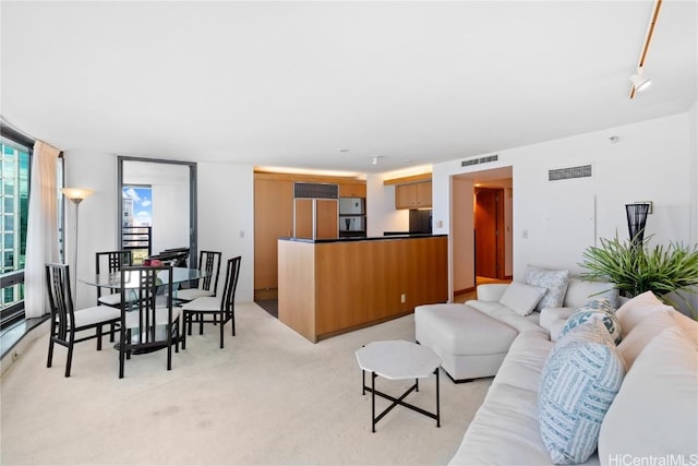 living room featuring rail lighting, light colored carpet, and expansive windows