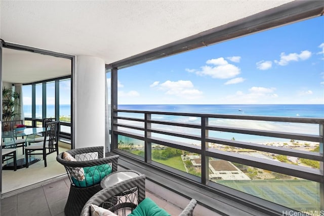 balcony featuring a view of the beach and a water view