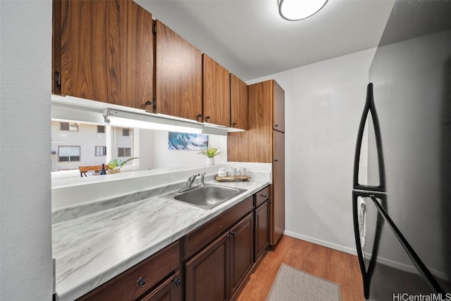 kitchen featuring black refrigerator, sink, and light hardwood / wood-style flooring