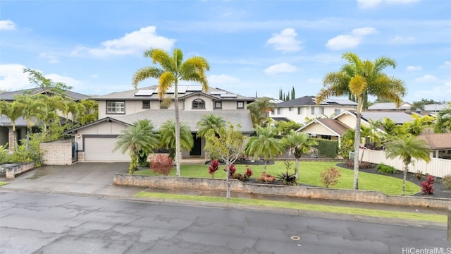 view of front of property featuring a garage, a front yard, and solar panels