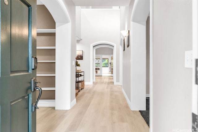 hall with light wood-type flooring and built in shelves