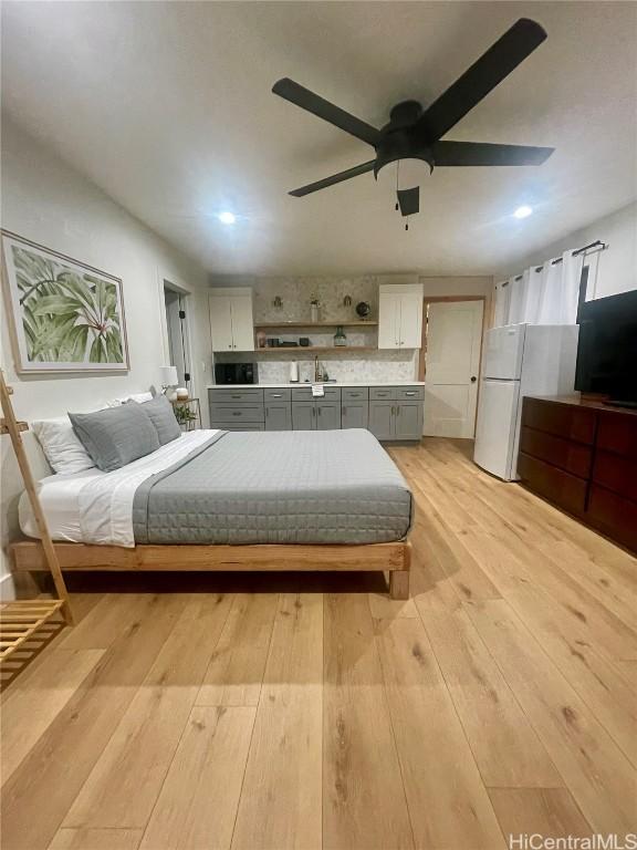 bedroom featuring white fridge, light wood-type flooring, sink, and ceiling fan