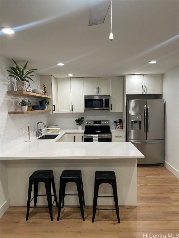 kitchen featuring white cabinetry, appliances with stainless steel finishes, kitchen peninsula, and a breakfast bar area