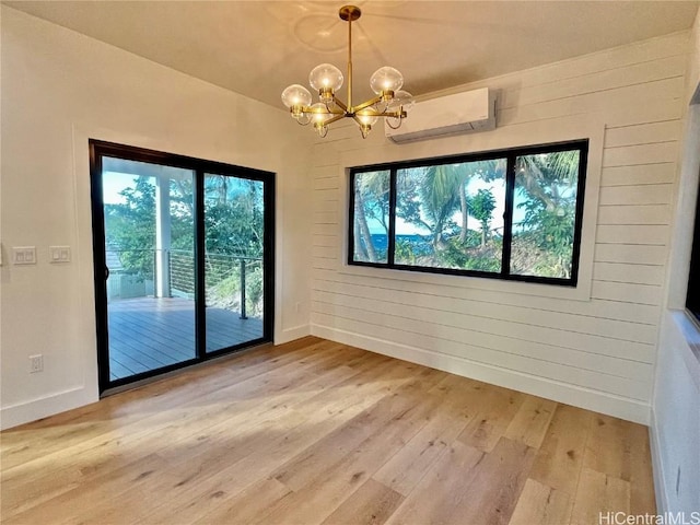 unfurnished dining area with hardwood / wood-style flooring, a wall mounted AC, and an inviting chandelier