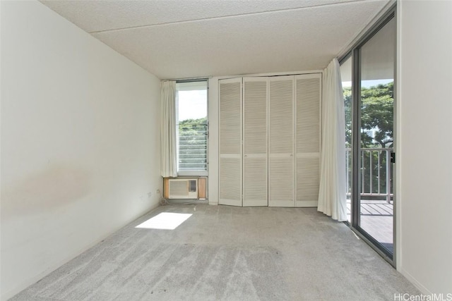 carpeted spare room with cooling unit, a textured ceiling, and a wall of windows