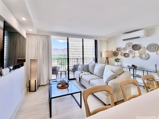 living room featuring floor to ceiling windows, a wall mounted AC, and light wood-type flooring