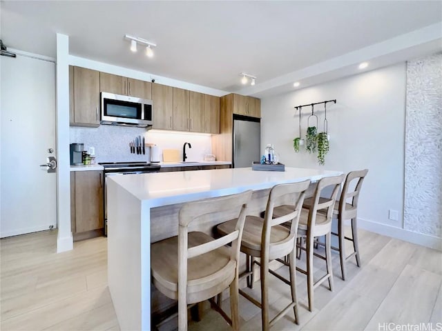 kitchen with stainless steel appliances, a kitchen breakfast bar, sink, and a kitchen island