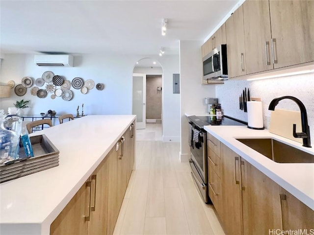 kitchen with sink, appliances with stainless steel finishes, a wall mounted AC, light brown cabinetry, and decorative backsplash