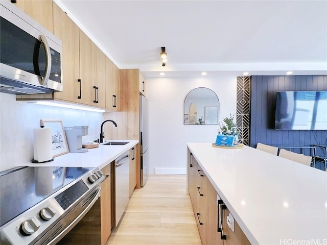 kitchen featuring recessed lighting, light countertops, appliances with stainless steel finishes, light brown cabinets, and a sink