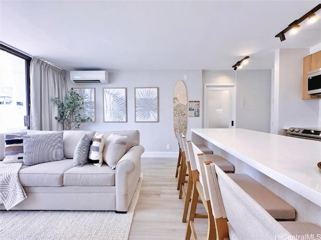 living room featuring an AC wall unit, light wood-style flooring, and baseboards