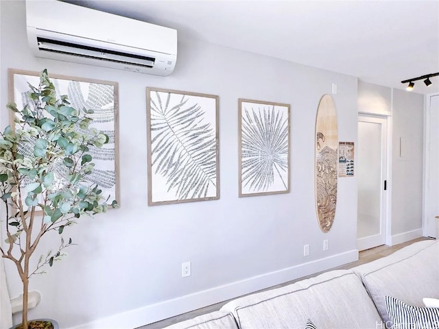 interior space with track lighting, a wall mounted air conditioner, and baseboards