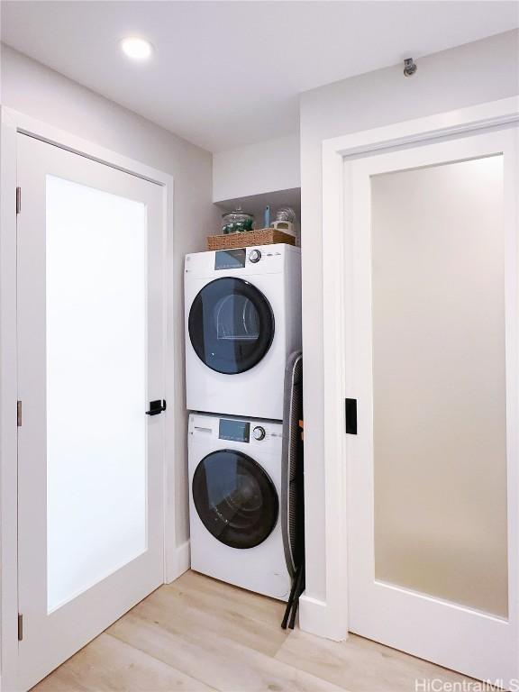 washroom featuring stacked washing maching and dryer, laundry area, light wood finished floors, and recessed lighting