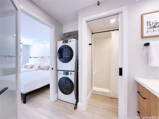 clothes washing area with light wood-type flooring, laundry area, and stacked washer / dryer