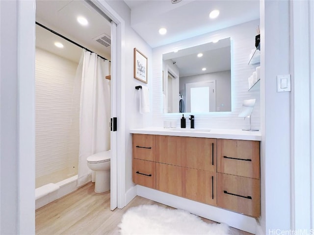 full bath featuring visible vents, toilet, a tile shower, vanity, and wood finished floors