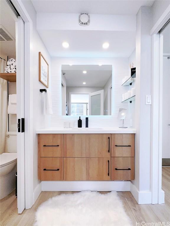 bathroom featuring toilet, wood finished floors, and vanity