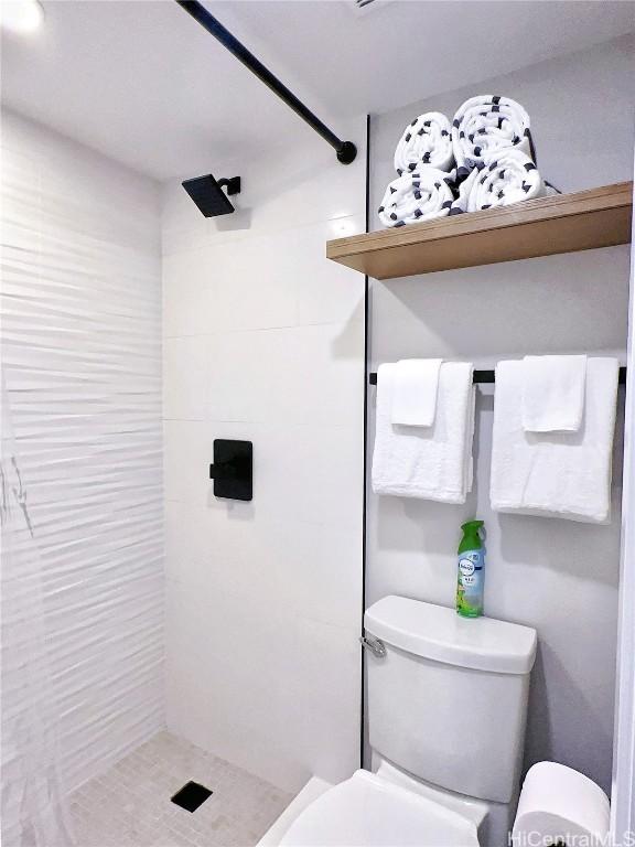 full bathroom featuring toilet and tiled shower