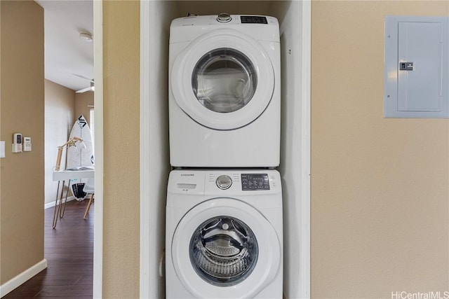 laundry room with stacked washer / drying machine, dark hardwood / wood-style flooring, and electric panel