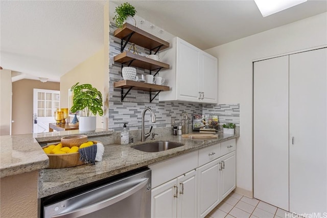 kitchen with light stone countertops, sink, stainless steel dishwasher, and white cabinets